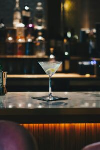 People socializing at a bar table with drinks and appetizers in the early evening.
