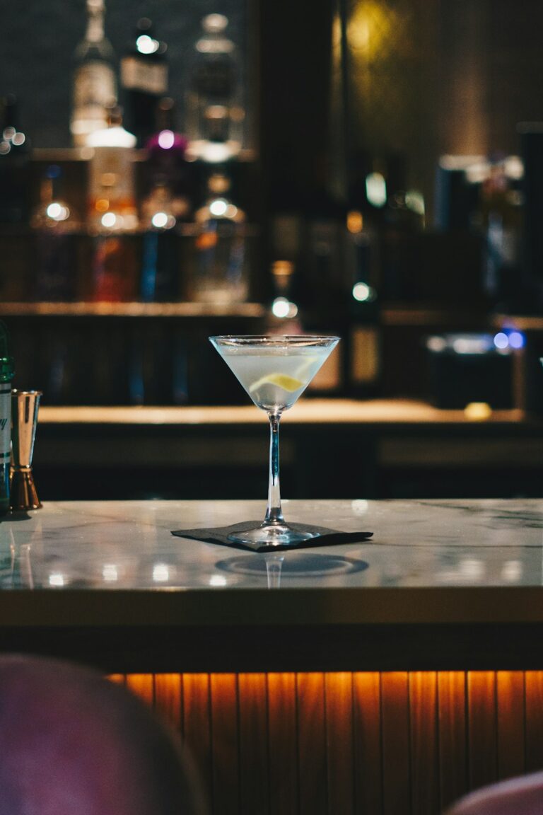 People socializing at a bar table with drinks and appetizers in the early evening.